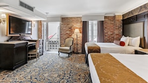 A hotel room with a large bed, a desk with a TV, a chair, and a patterned carpet. - Place d'Armes Hotel (New Orleans)