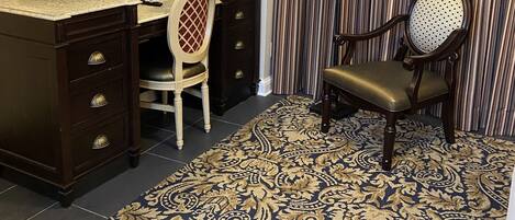 Une chambre d’hôtel équipée d’un bureau, d’une chaise, d’une télévision et d’une moquette à motifs.