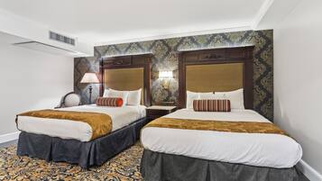 A hotel room with two beds, a patterned carpet, and a decorative wall.