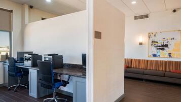 A modern office space with a desk area, office chairs, and a sofa.