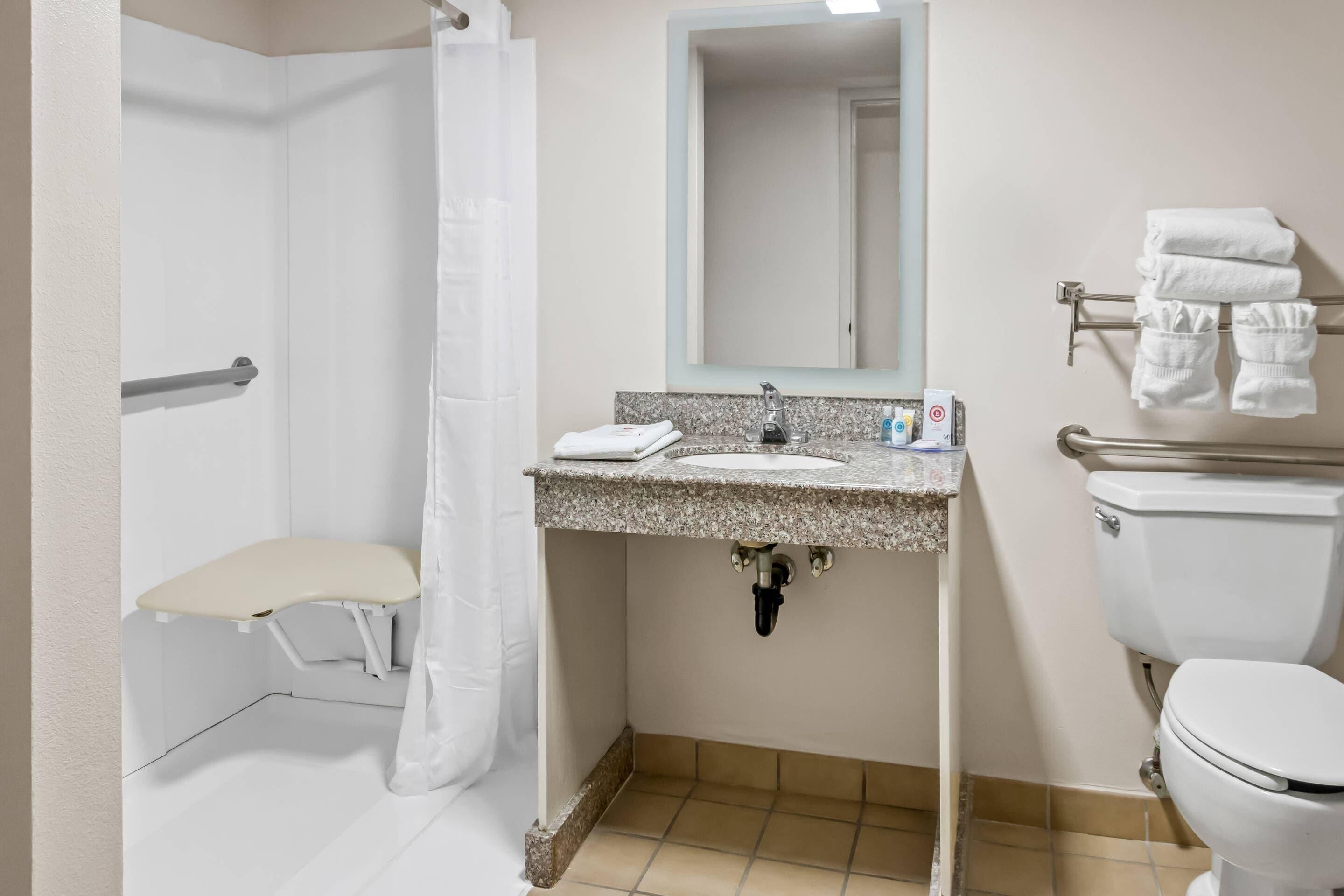 A bathroom with a shower, toilet, sink, and towel rack.