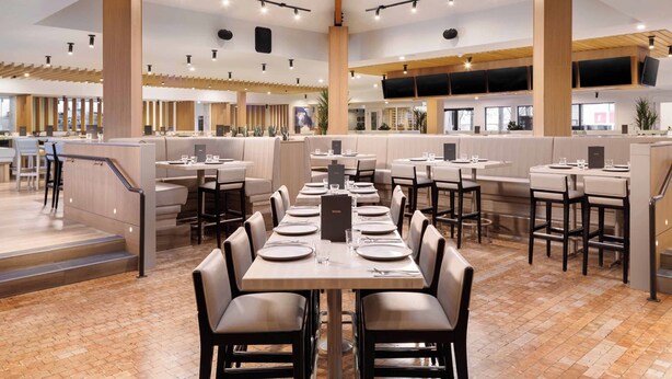 Un restaurante espacioso con techos altos, vigas de madera y una decoración interior moderna.