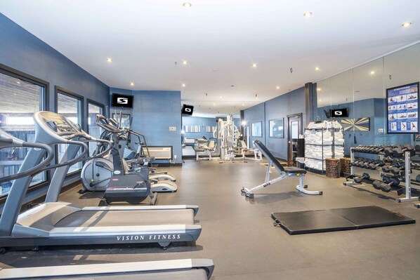 Un gimnasio moderno con cintas de correr, elípticas y equipamiento de levantamiento de pesas.