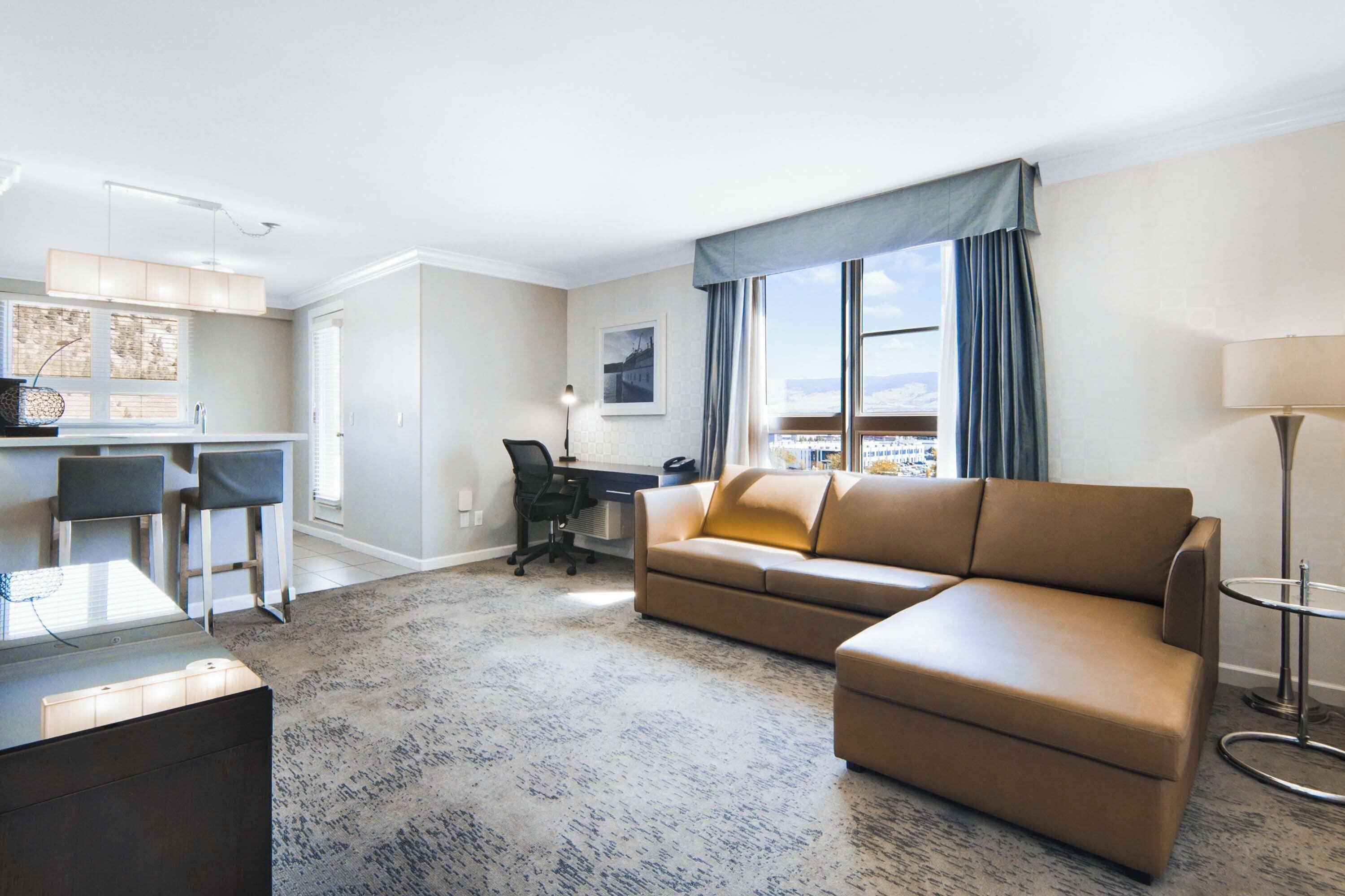 Een moderne hotelkamer met een bank, een bureau, een stoel en uitzicht op de stad.