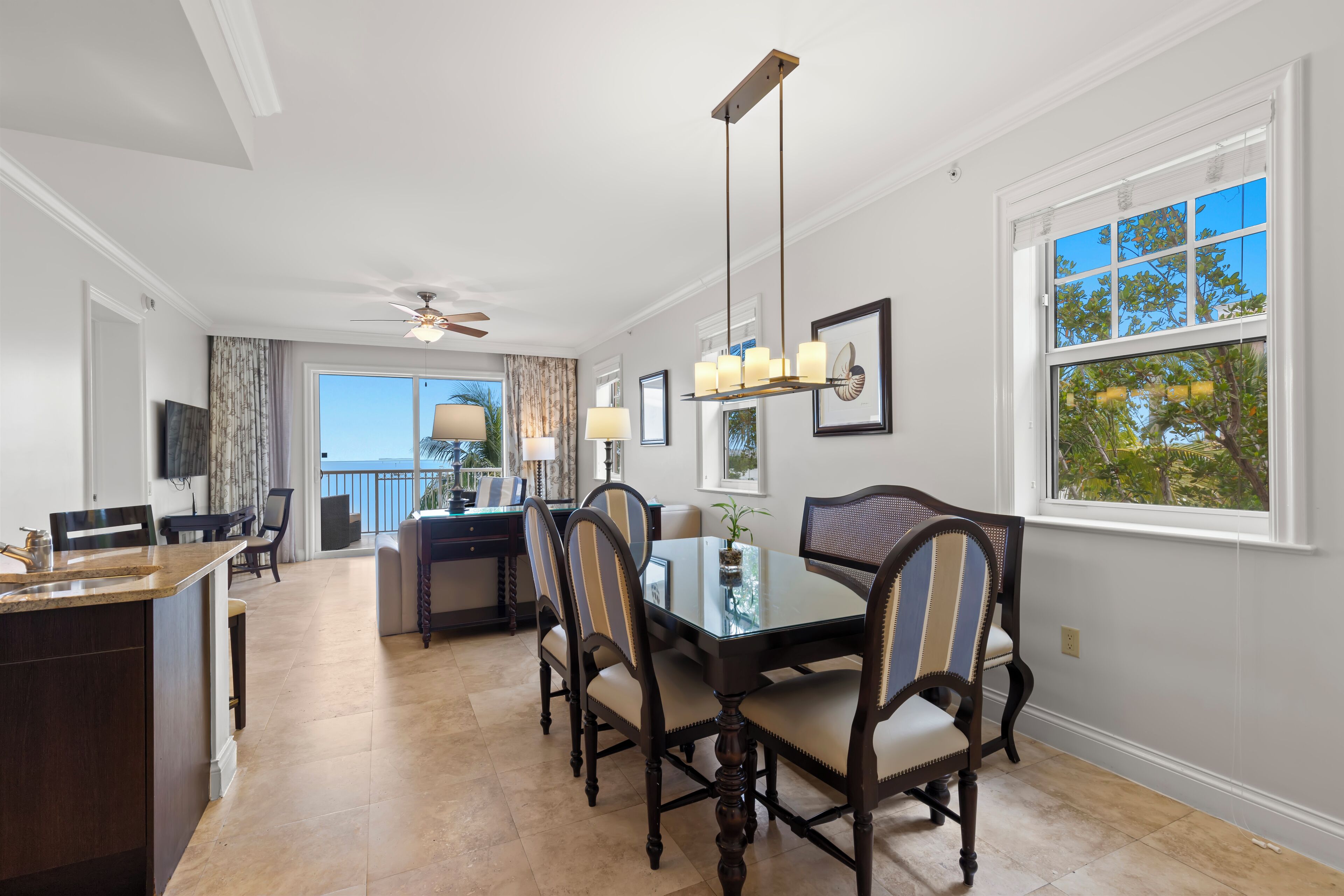 A dining area with a glass table, six chairs, and a chandelier.