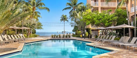 Een buitenzwembad, parasols bij het zwembad en ligstoelen