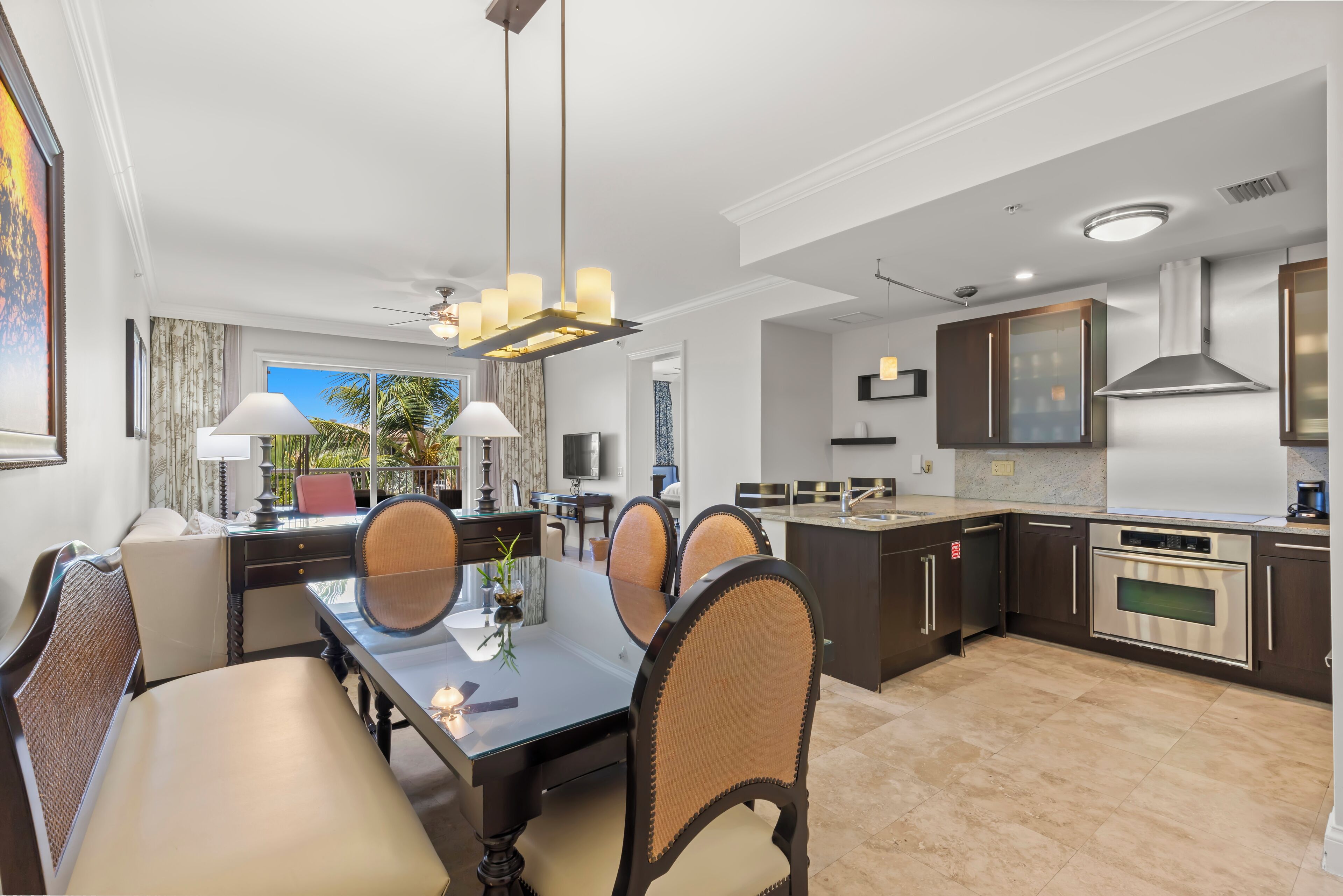 A modern kitchen with a dining area, featuring a large island, stainless steel appliances, and a ceiling fan.