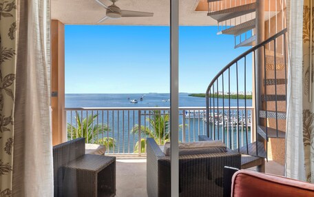 A balcony with wicker furniture, a view of the sea, and a spiral staircase.