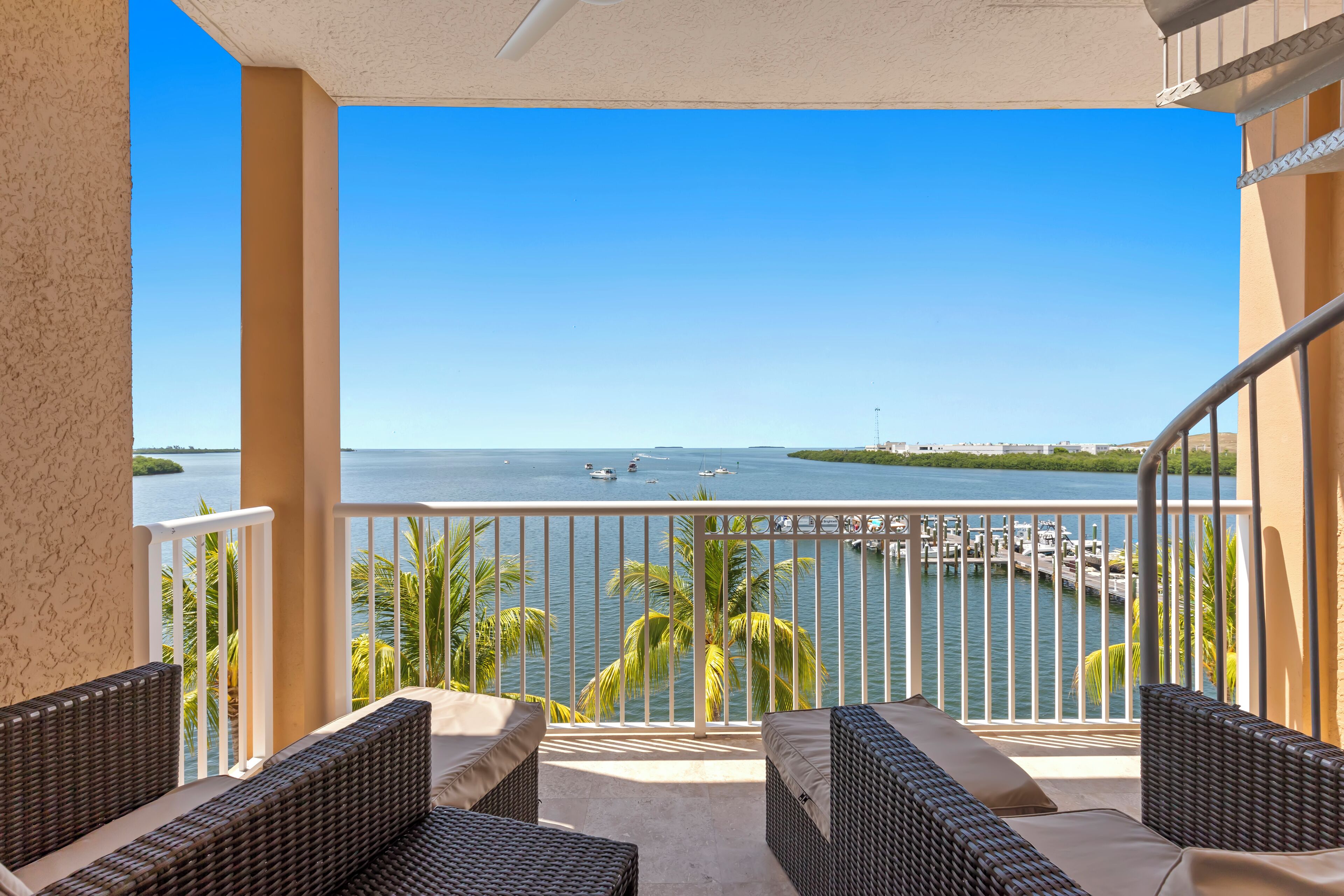 A balcony with wicker furniture and a view of the water.