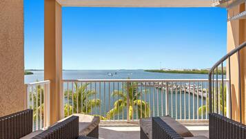 A balcony with wicker furniture and a view of the water.