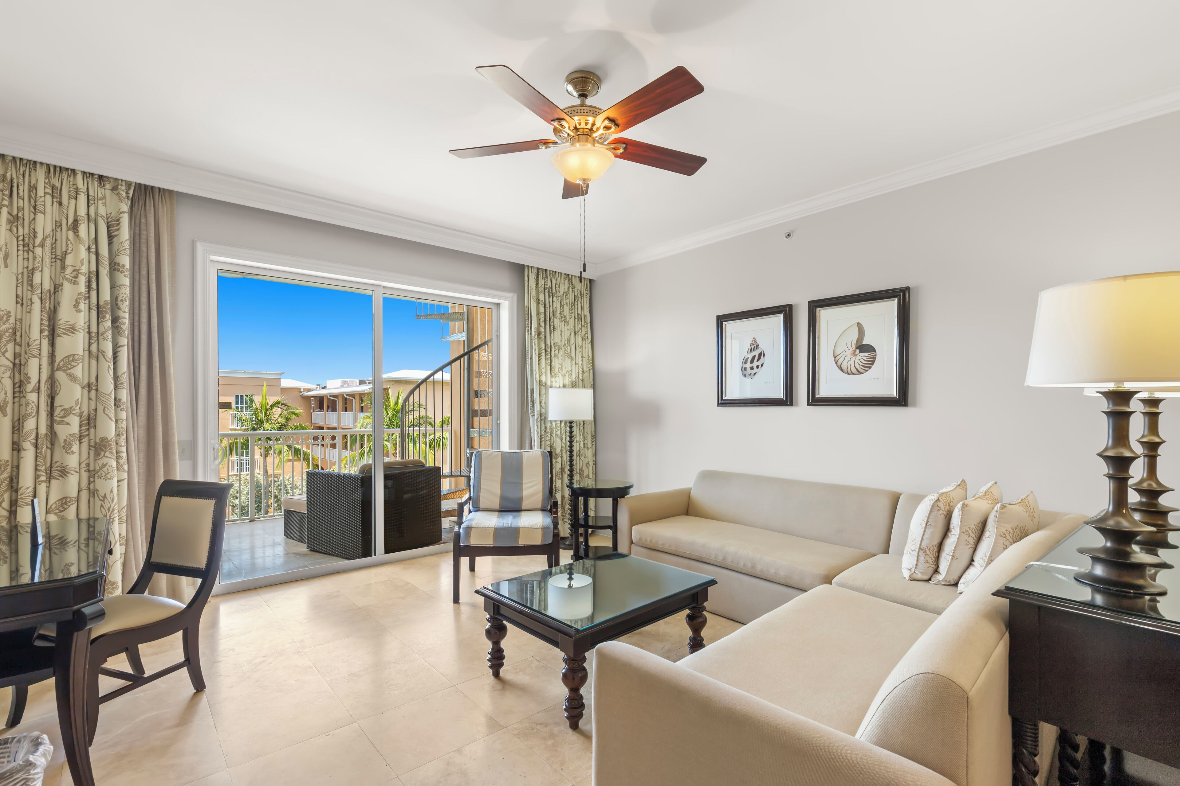 A spacious living room with a sofa, armchairs, a coffee table, and a ceiling fan.
