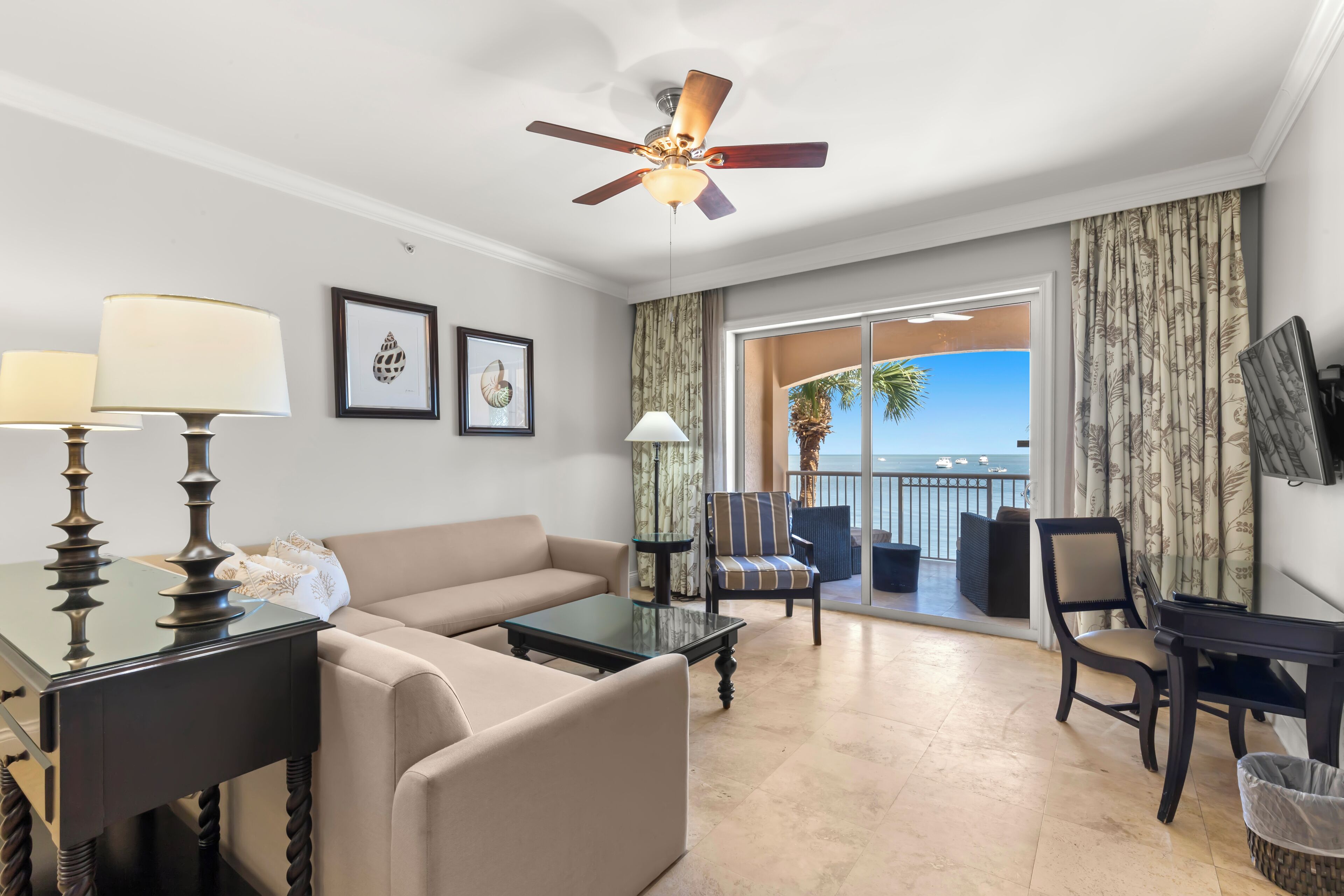 Una habitación de hotel con balcón, sofá, mesa de centro y escritorio.
