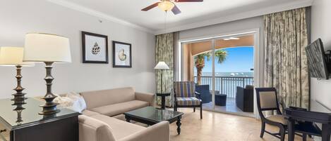 Una habitación de hotel con balcón, sofá, mesa de centro y escritorio.