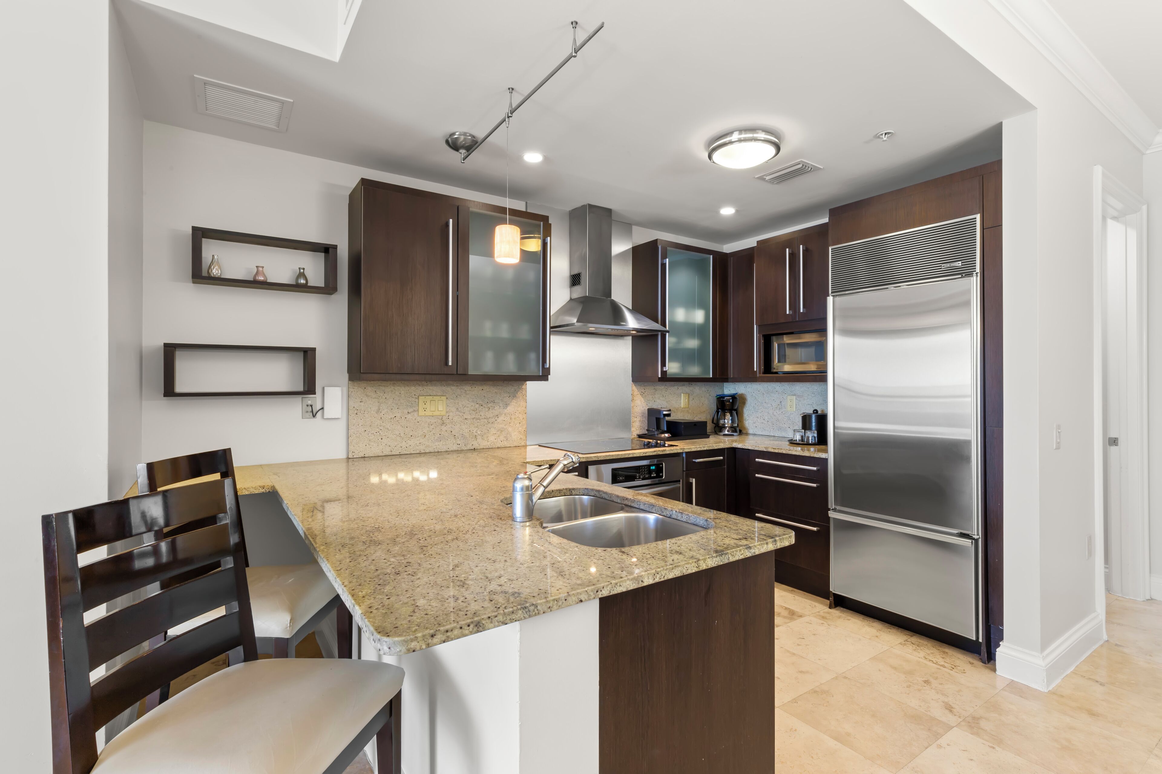 A modern kitchen with granite countertops, stainless steel appliances, and dark wood cabinets.