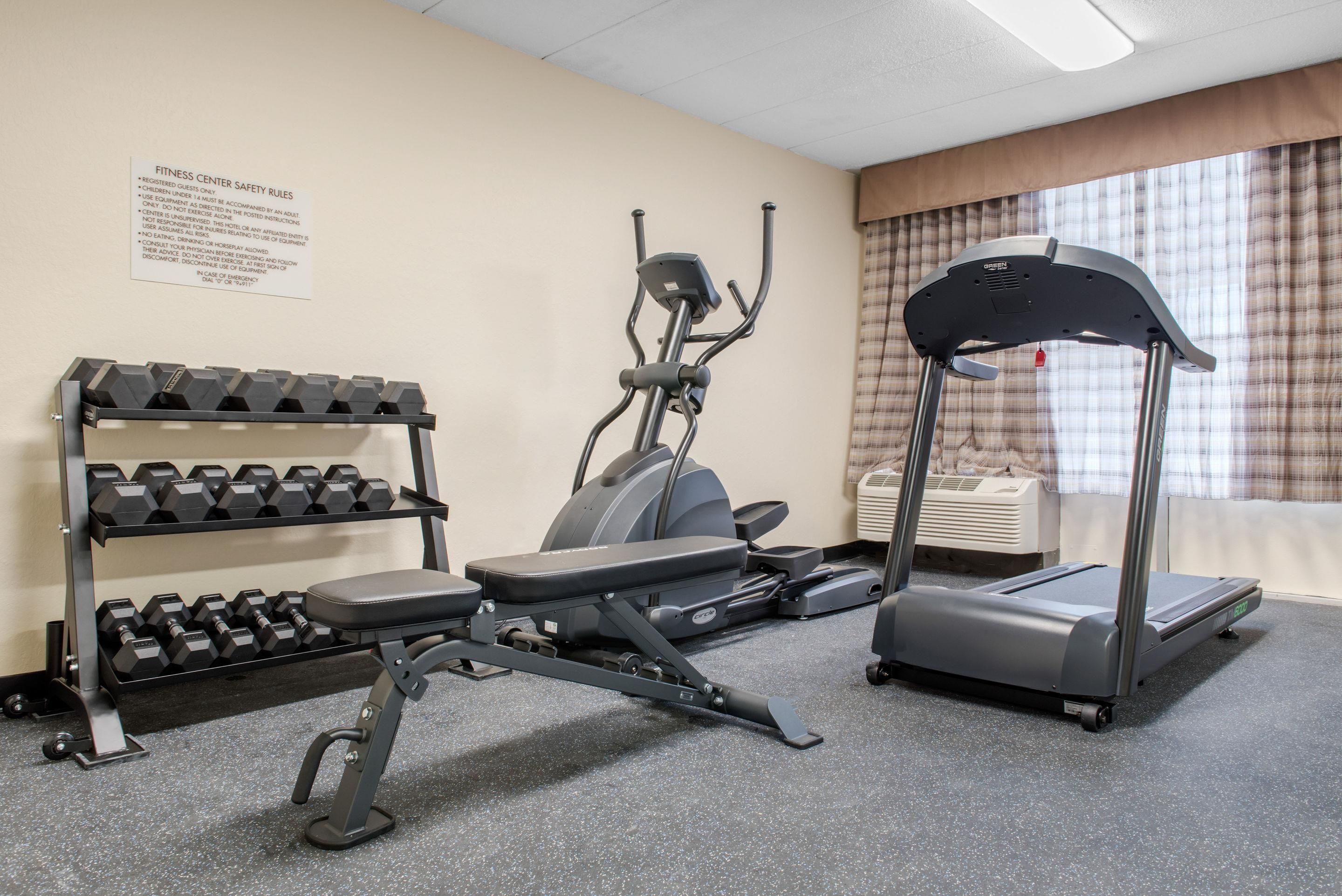 A fitness center with dumbbells, an elliptical, and a treadmill.