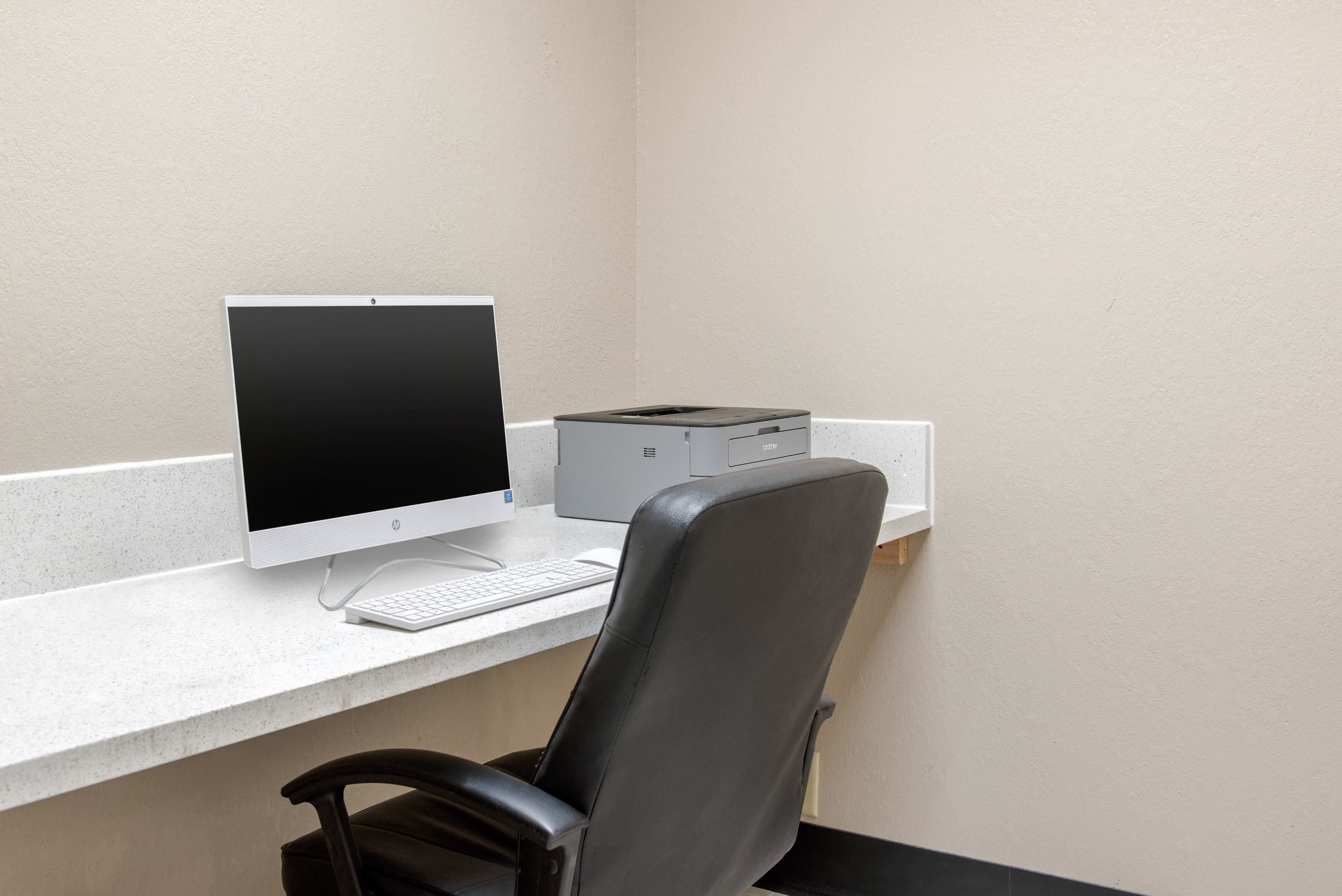 A computer desk with a monitor, keyboard, and printer.