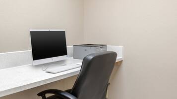 A computer desk with a monitor, keyboard, and printer.