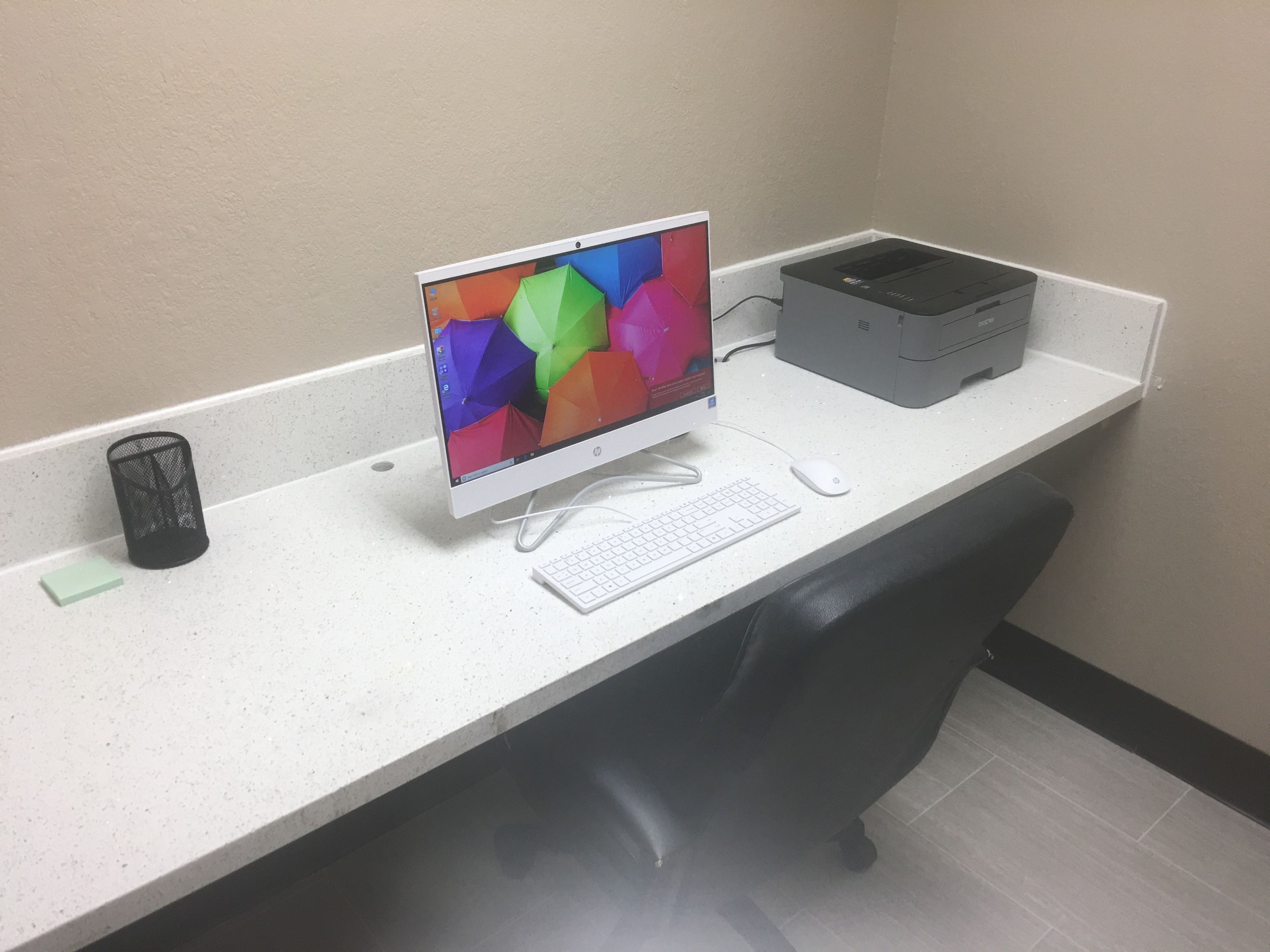 Un escritorio blanco con computadora de escritorio, teclado, ratón e impresora.