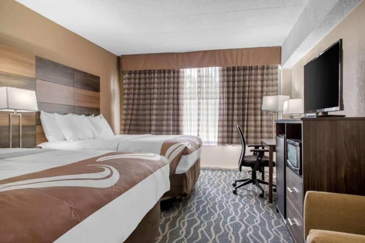 Una habitación de hotel con cama, escritorio, televisor y una silla.