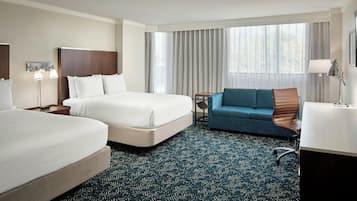 Habitación de hotel con una cama grande, un sofá, un escritorio con silla y una ventana con cortinas.