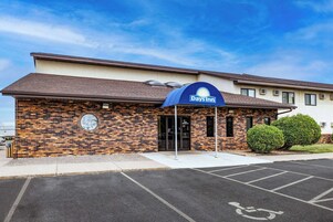 Un hotel Days Inn con fachada de ladrillo, un toldo azul y un estacionamiento con plazas para discapacitados.