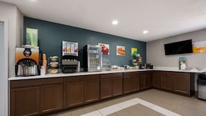 A hotel reception area with a coffee machine, refrigerator, and various food items on the counter. - Quality Inn University Area (Farmville)