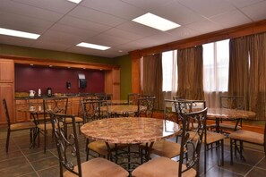 A conference room with round tables and chairs, a kitchen area, and large windows with curtains. - Americas Best Value Inn & Suites Kansas City (Kansas City)