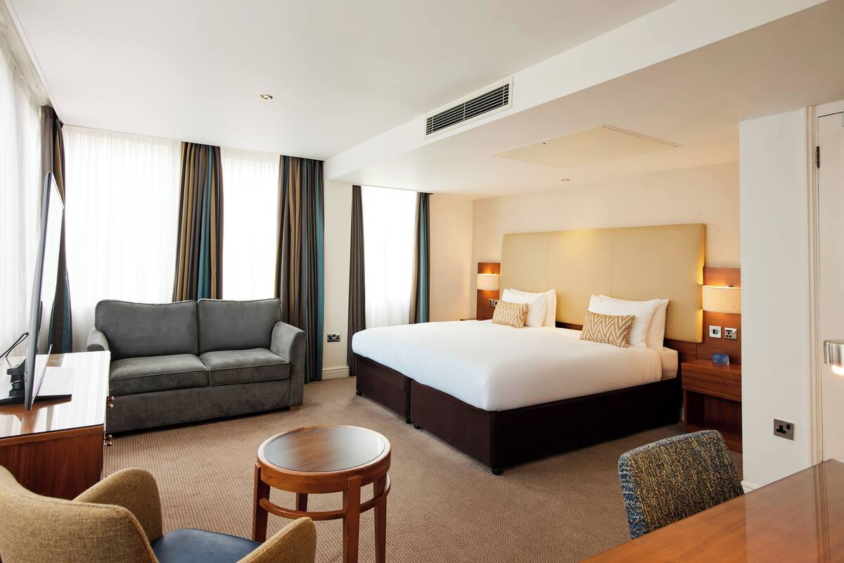 Ett hotellrum med en stor säng, en soffa, ett skrivbord och en stol.