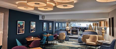 A modern hotel lobby with round ceiling lights, comfortable seating, and artwork on the walls.