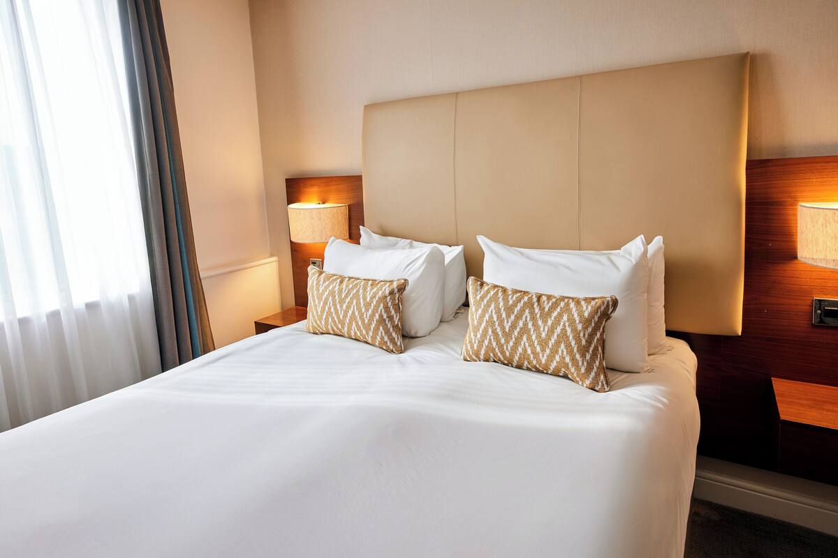 Ett hotellrum med en stor säng, två sänglampor och en sänggavel.
