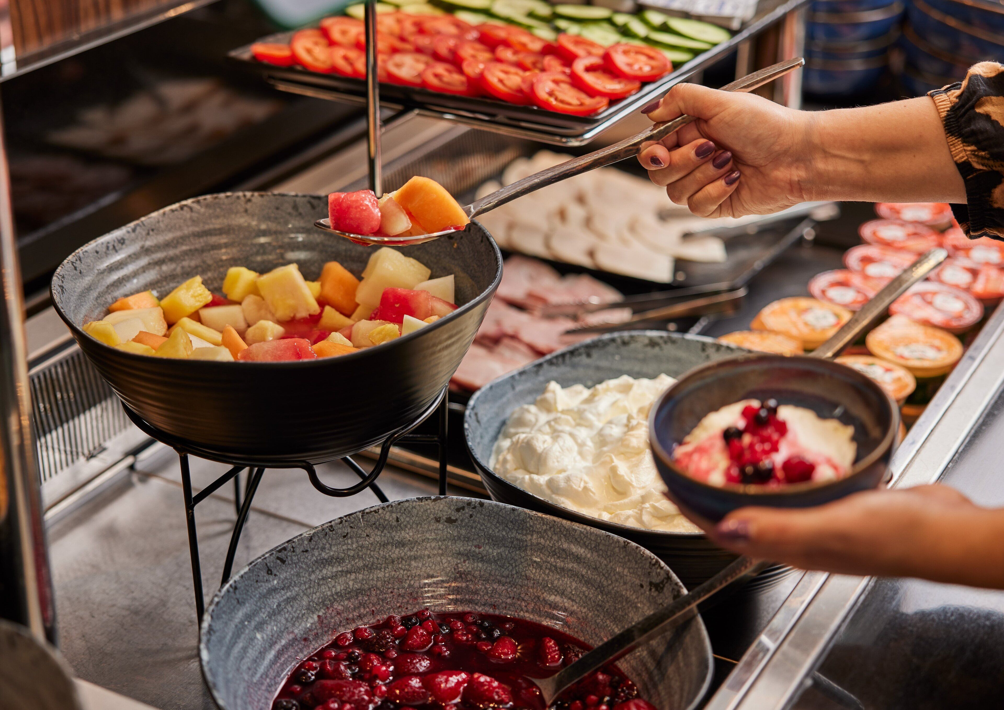 Ein Buffet mit verschiedenen Speisen, darunter Obst, Gemüse und Desserts.