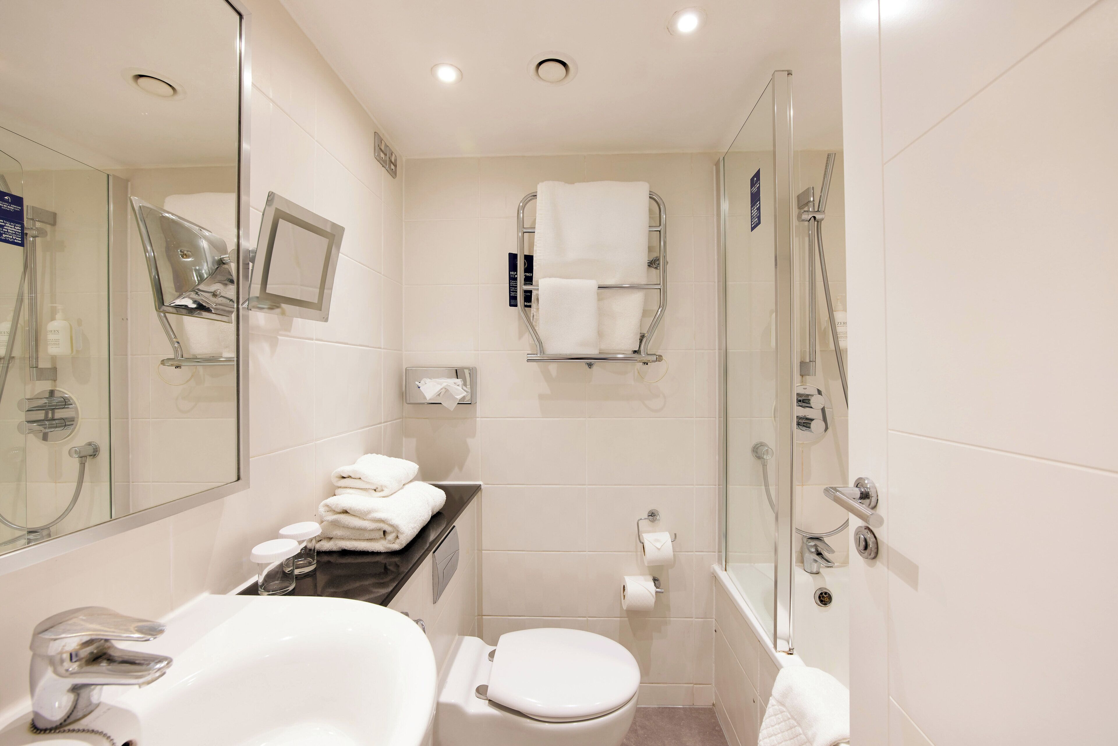 A modern bathroom with a glass-enclosed shower, a white sink, and a toilet.