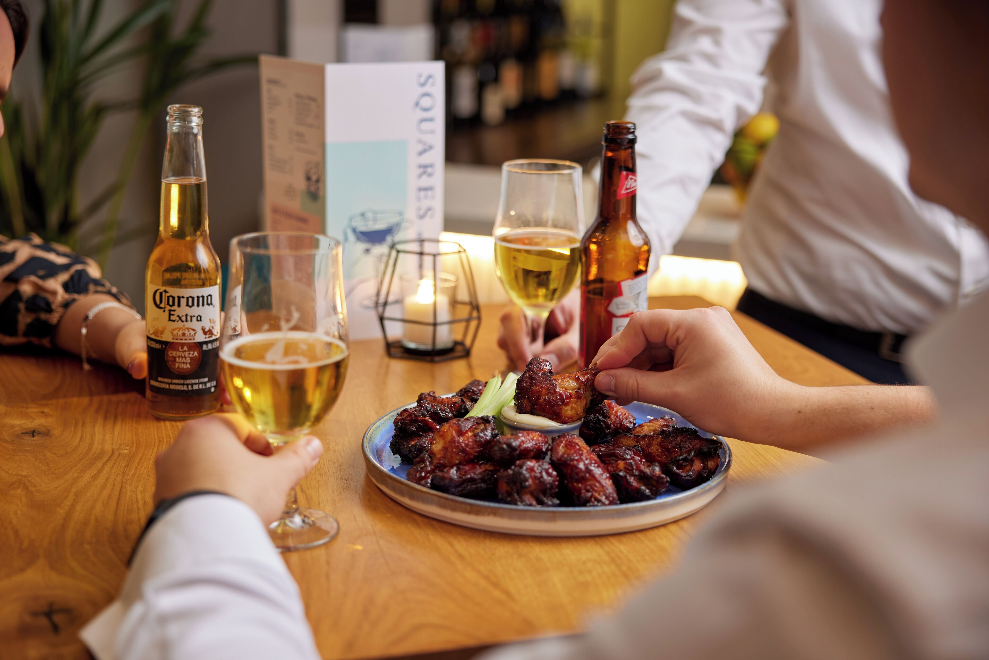 A dining table with a plate of food, a bottle of Corona beer, and glasses of beer.