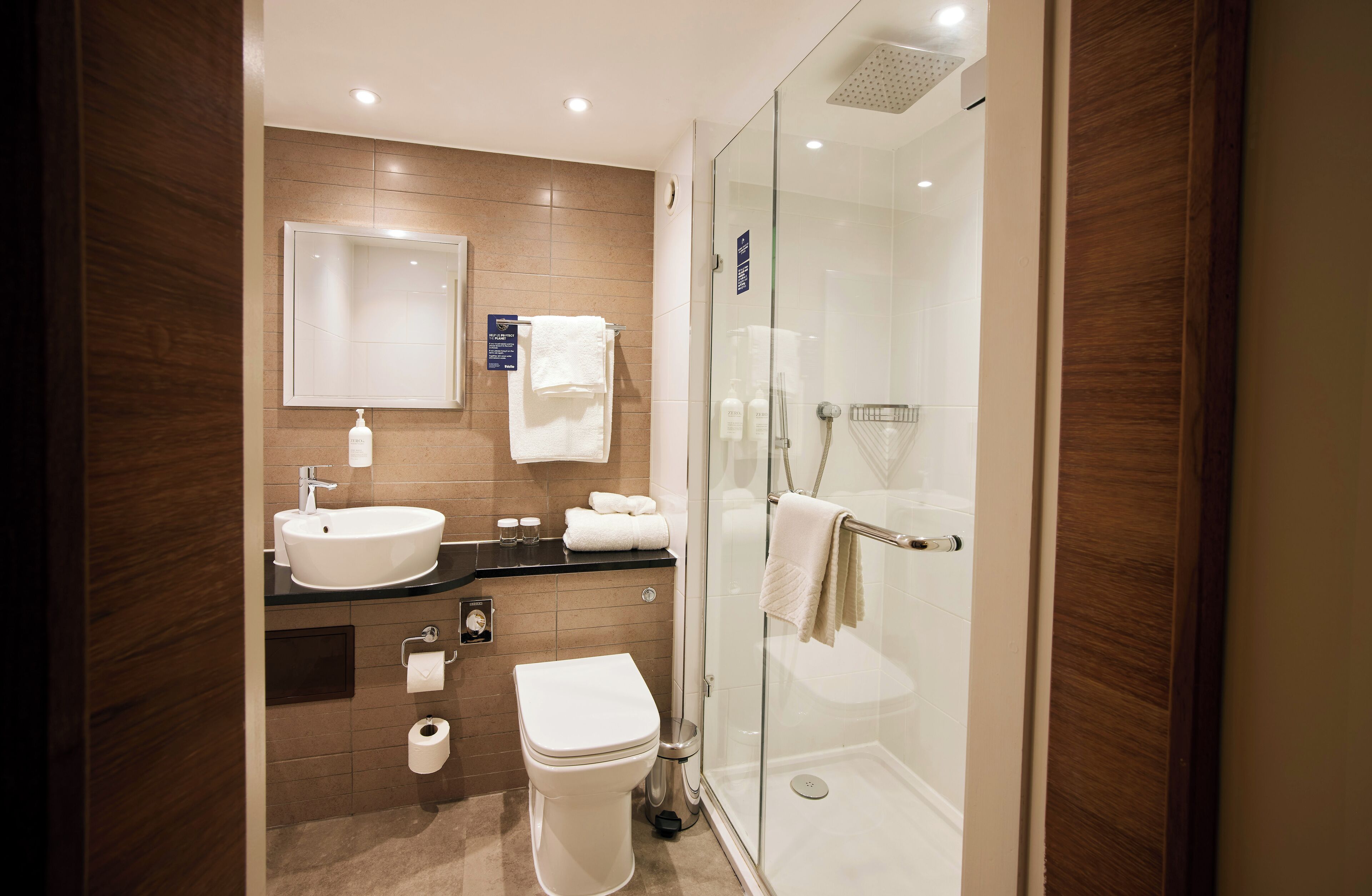 Un baño moderno con lavamanos, inodoro y ducha con mampara de vidrio.