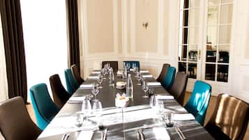 Un comedor formal con una larga mesa dispuesta para una comida, rodeada de sillas.