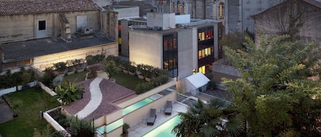 Un patio con piscina, sillas de descanso y jardín.
