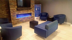 A lobby with a stone wall, a fish tank, and seating areas.
