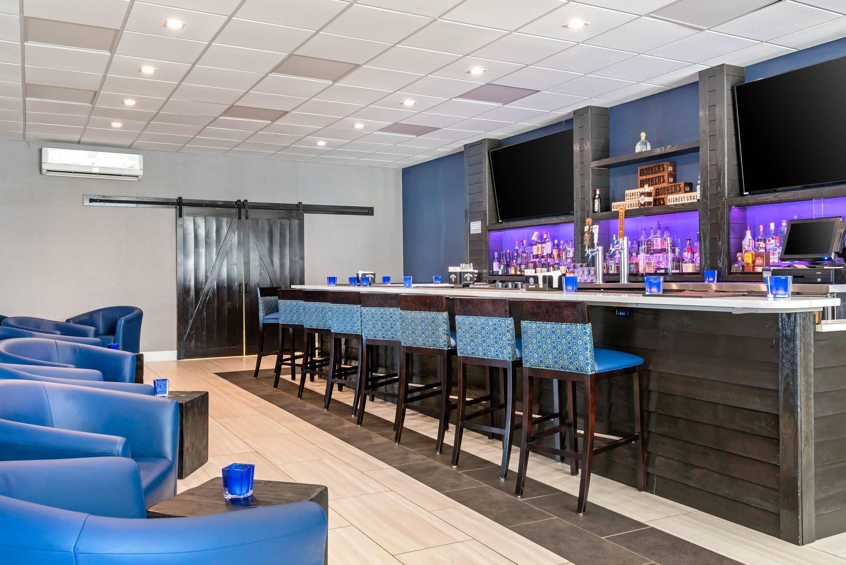 Zona de bar con mostrador, taburetes y un área de asientos con sillas azules.