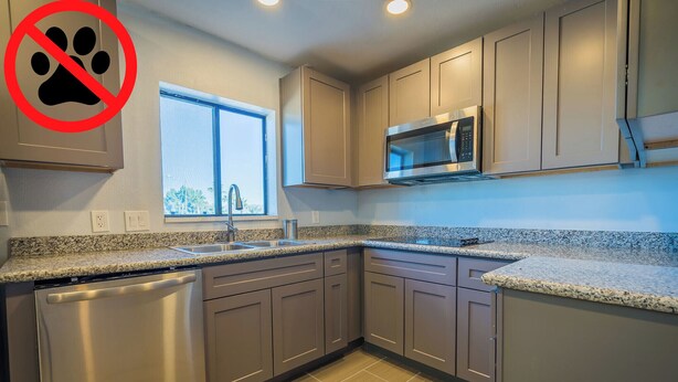 A modern kitchen with granite countertops, stainless steel appliances, and light wood cabinets.