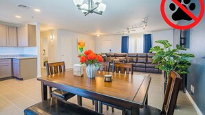 A modern living room with a dining area, a kitchen, and a living room with a sofa and a coffee table.
