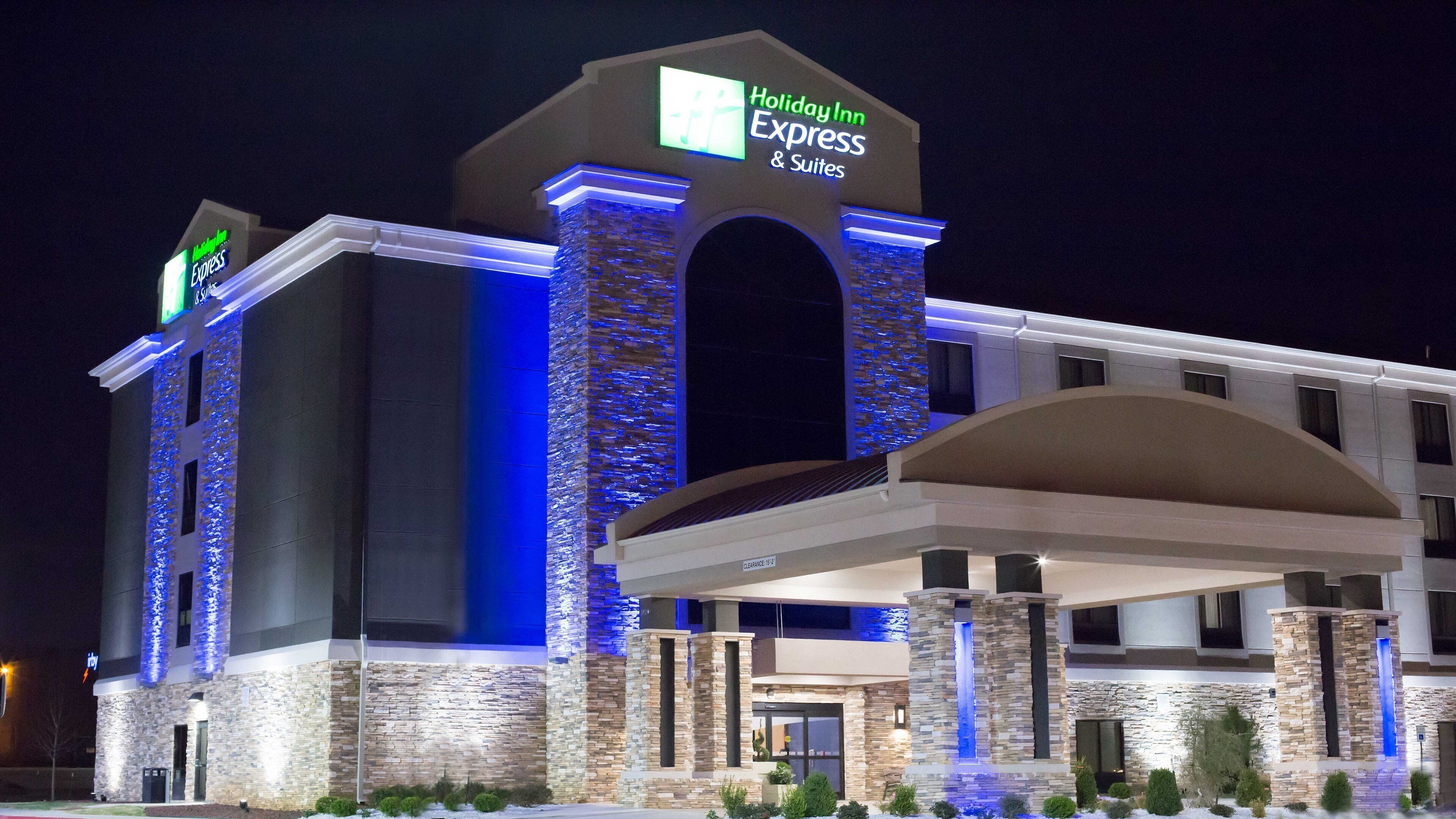 Un hotel Holiday Inn Express & Suites con fachada de piedra, entrada cubierta y un letrero que indica una altura libre de 15 pies.