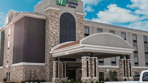 Un hotel Holiday Inn Express & Suites con fachada de piedra y entrada cubierta.