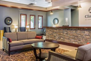 A lobby with a sofa, a round table, and a stone wall.