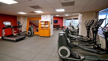Een sportschool met loopbanden, elliptische trainers en een gewichtrek.