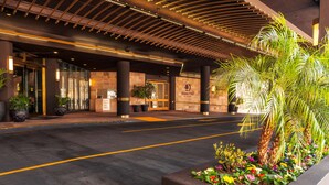 A hotel entrance with a modern design, featuring a glass facade, a reception desk, and a sign for 'DoubleTree by Hilton'.