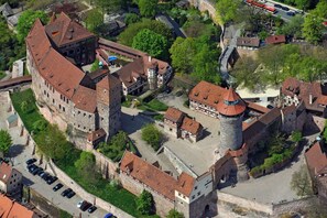 An aerial view of a historic town with a prominent castle, narrow streets, and traditional buildings.