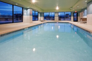 An indoor swimming pool with clear blue water, surrounded by windows offering views of the outside. - Holiday Inn Express Roseville-St. Paul by IHG (Roseville)