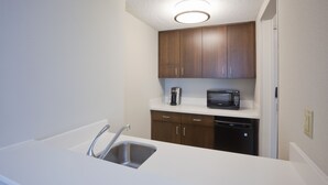 A kitchen with a stainless steel sink, wooden cabinets, a microwave, and a dishwasher. - Holiday Inn Express Roseville-St. Paul by IHG (Roseville)