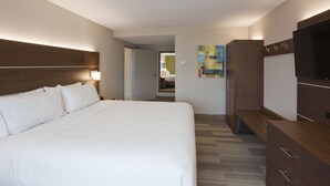 A hotel room with a large bed, a TV, a wooden dresser, and a door leading to a bathroom. - Holiday Inn Express Roseville-St. Paul by IHG (Roseville)