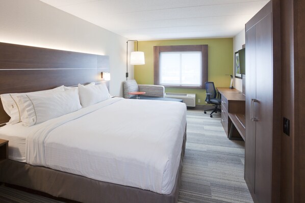 Ein Hotelzimmer mit einem großen Bett, einem Schreibtisch, einem Stuhl und einem Fernseher.